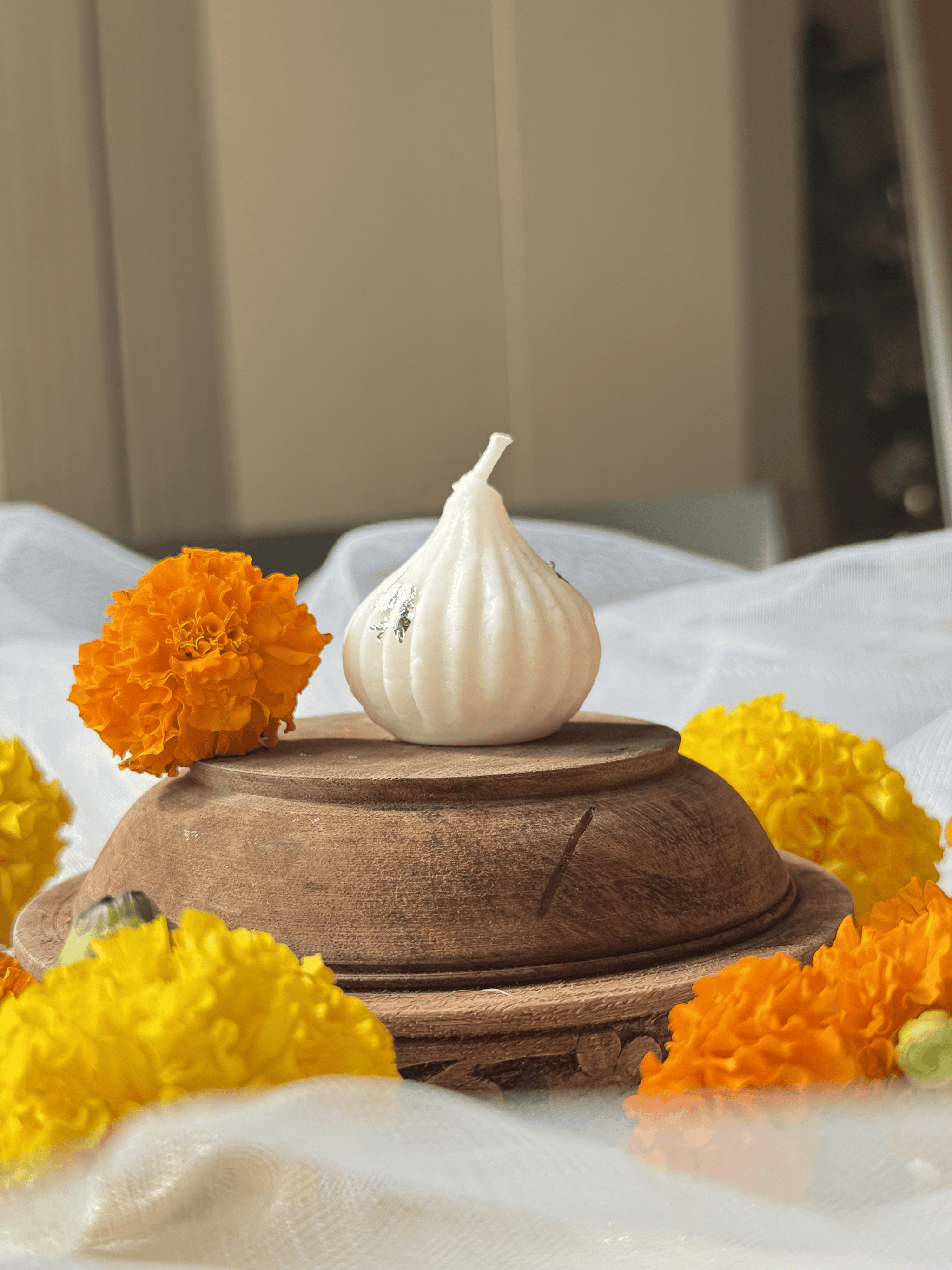Modak candle surrounded by festive yellow and orange marigolds